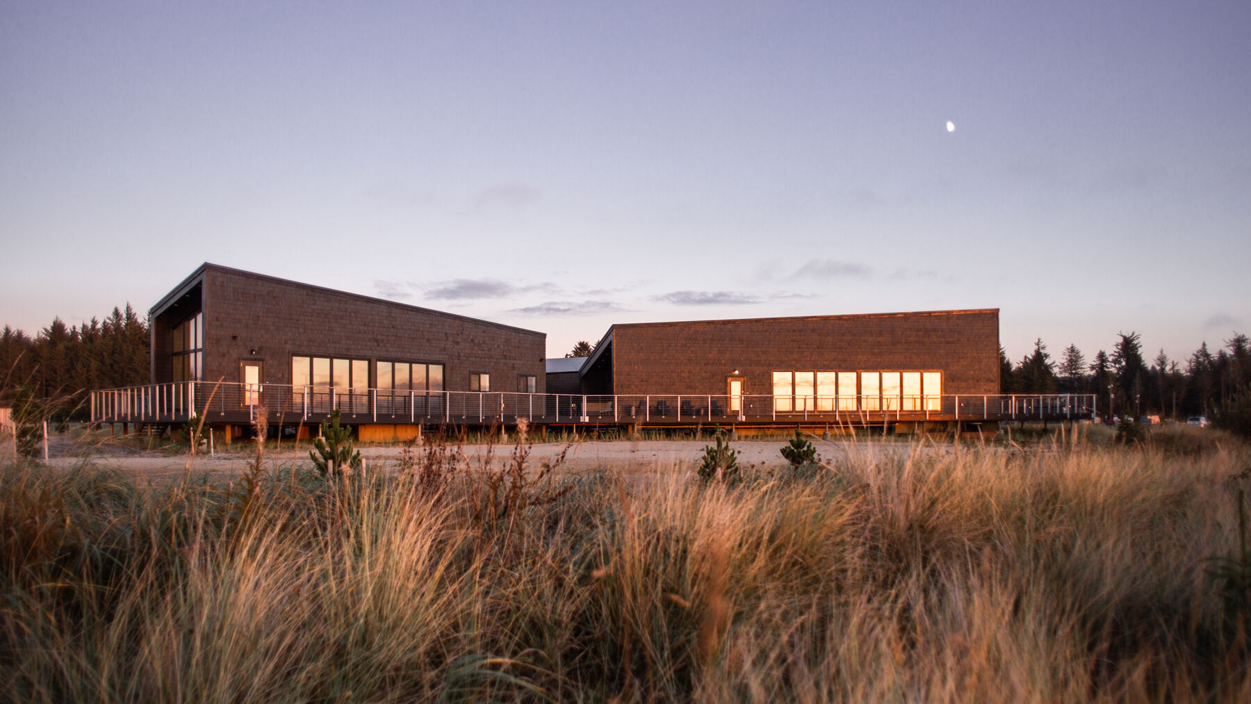 A modern building with large windows set amid grassy fields under an evening sky, capturing a peaceful and serene landscape.