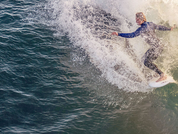 A surfer in a wetsuit rides a wave, carving through the ocean water with skill and speed.