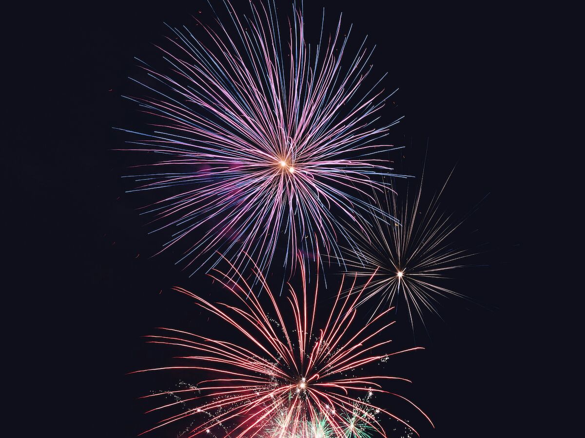 A colorful display of fireworks bursts against a dark night sky, creating a vibrant and festive atmosphere with bright, vivid hues.