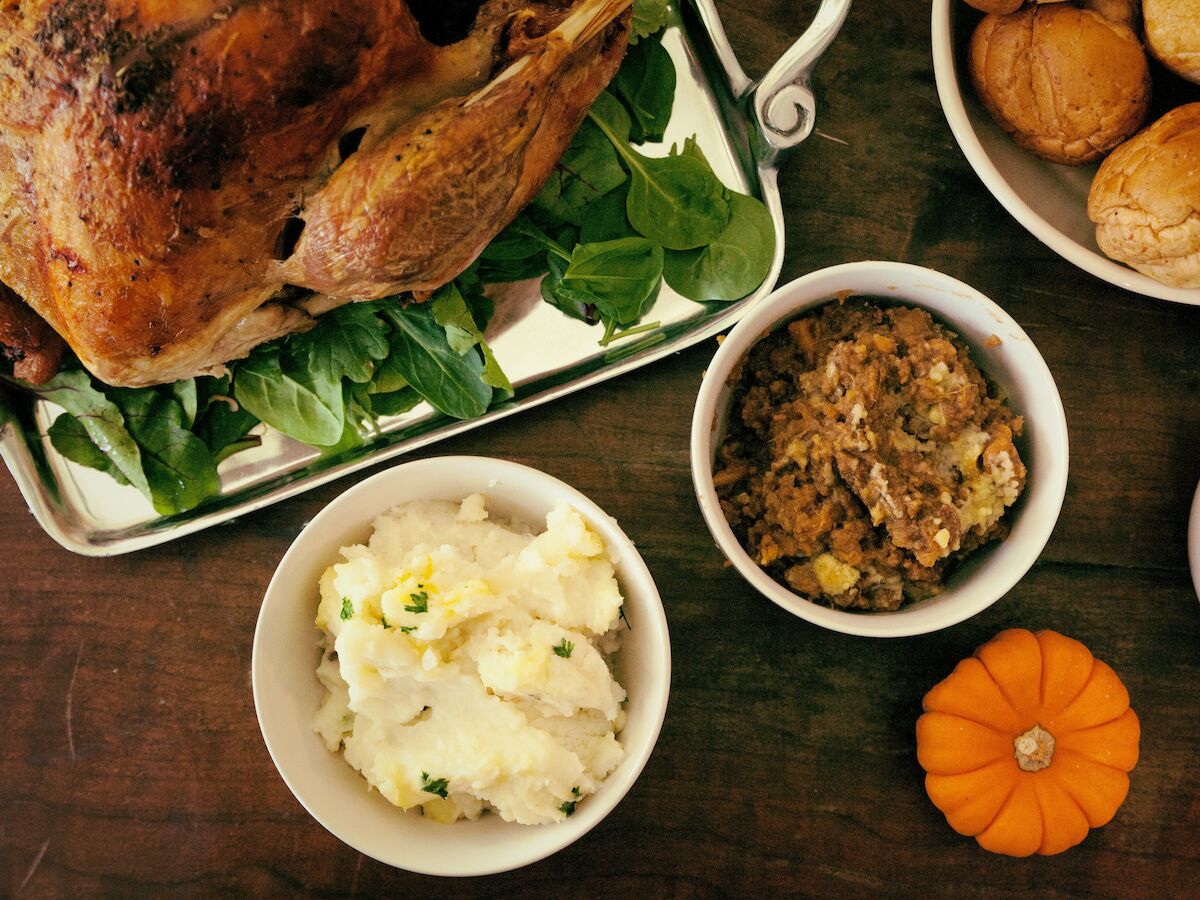Roasted chicken with wilted greens and stuffing-like grains, plus mashed potatoes and roasted squash on a platter.